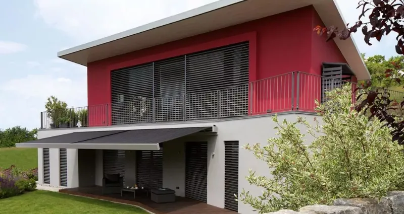 Rot weißes Haus mit dunklen Außenjalousien