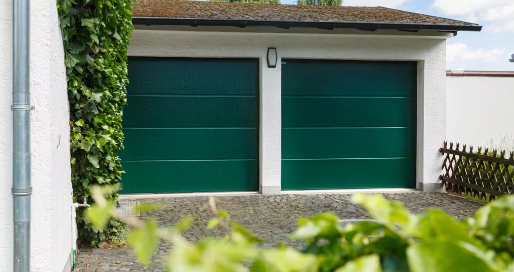 Abendliche Terrasse mit beleuchtetem rotem Sonnenschirm Zwei grüne Garagentore