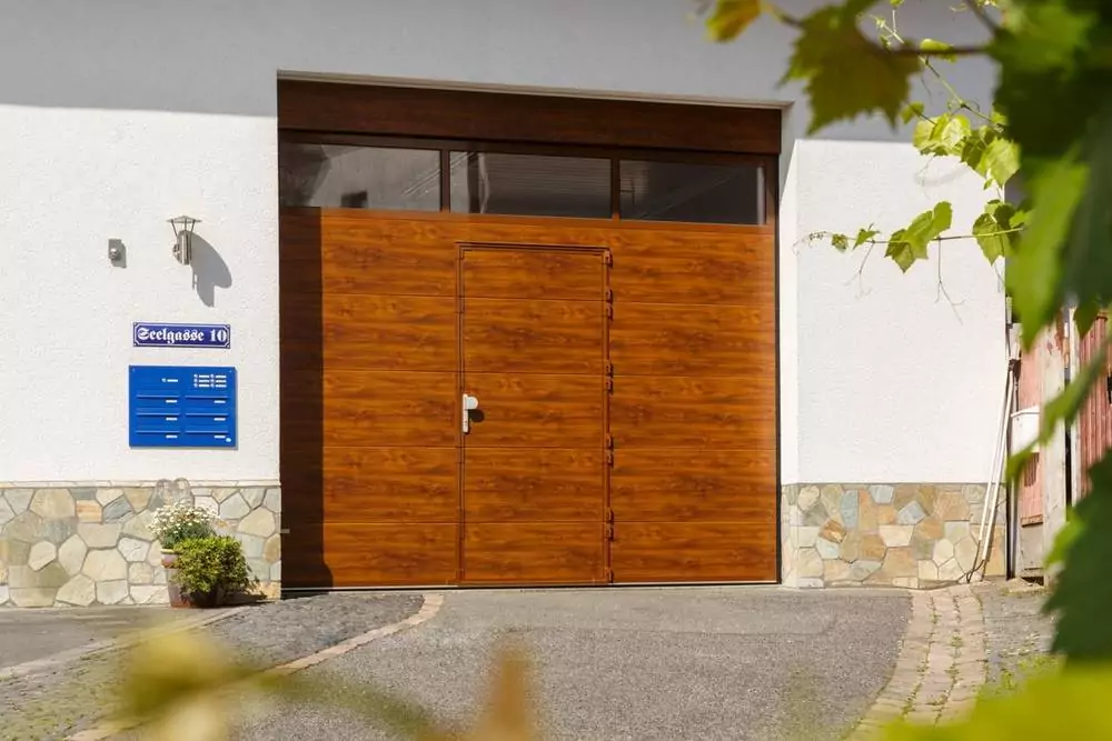 Abendliche Terrasse mit beleuchtetem rotem Sonnenschirm Garagentor in Holzoptik