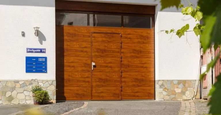 Abendliche Terrasse mit beleuchtetem rotem Sonnenschirm Garagentor in Holzoptik