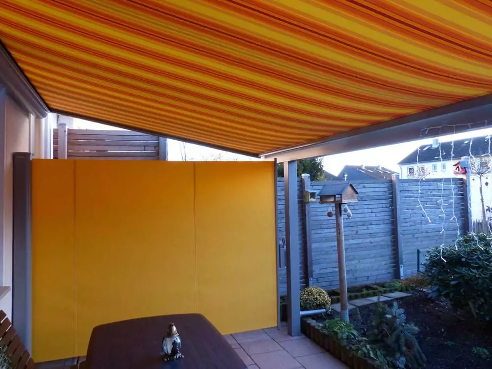 Markise als Sonnenschutz Gelb orange gestreifte Terrassenmarkise über dem Sitzbereich