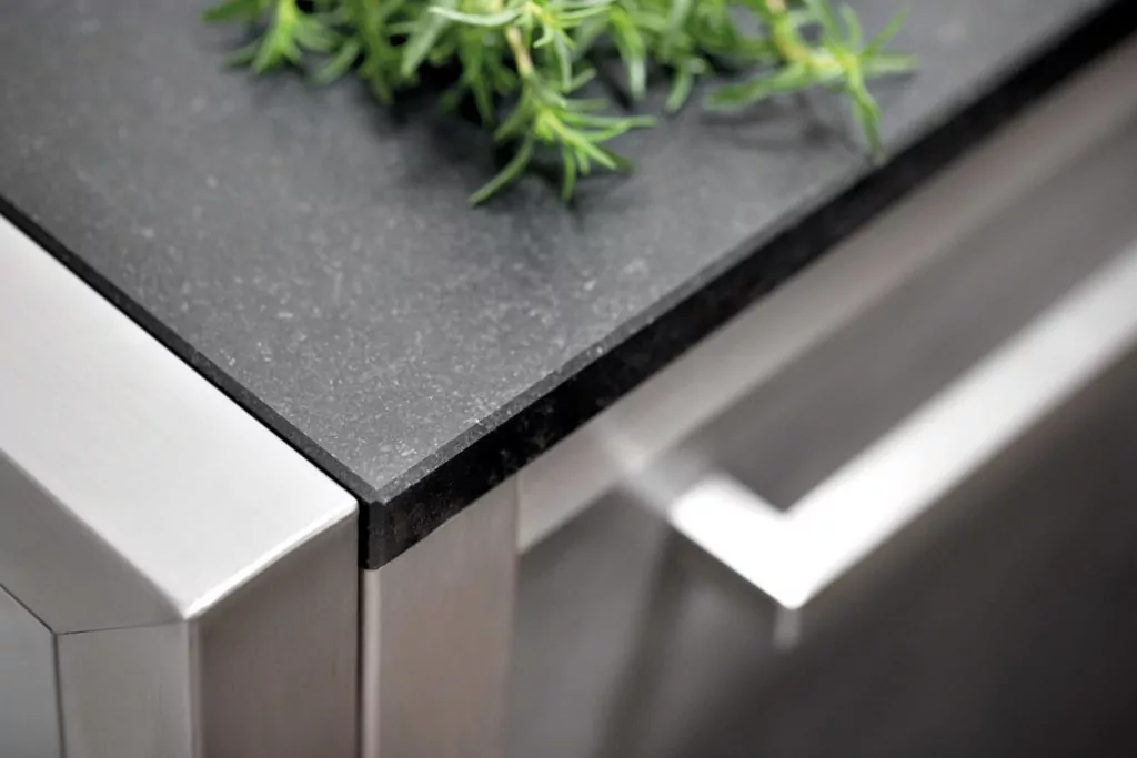 Abendliche Terrasse mit beleuchtetem rotem Sonnenschirm Edelstahlküche mit schwarzer Steinplatte