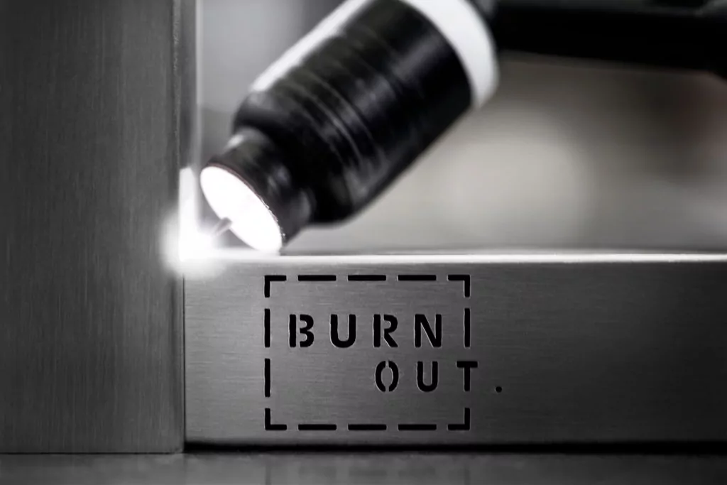 Abendliche Terrasse mit beleuchtetem rotem Sonnenschirm Burn Out Logo in Metallschiene