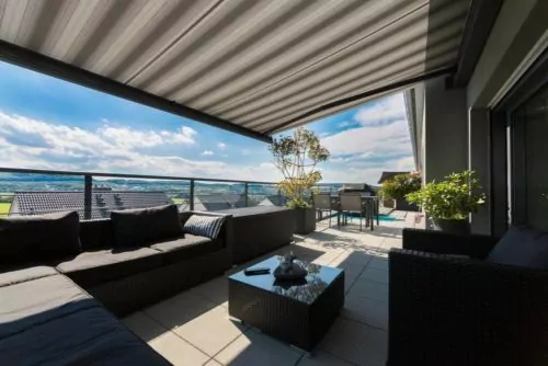 Terrasse mit Pergolamarkise Grau gestreifte Pergola Markise über dem Sitzbereich einer Terrasse