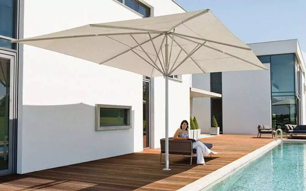 Abendliche Terrasse mit beleuchtetem rotem Sonnenschirm Cremefarbener Sonnenschirm über der Sitzbank