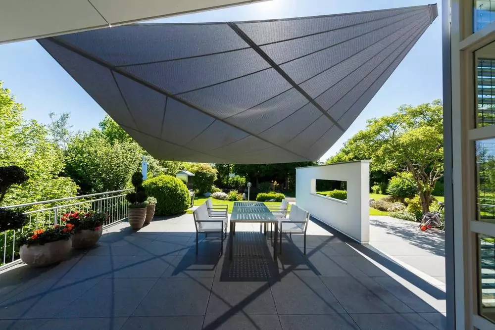 Automatische Terrassenbeschattung mit Fernbedienung Graues Sonnensegel über dem Sitzbereich