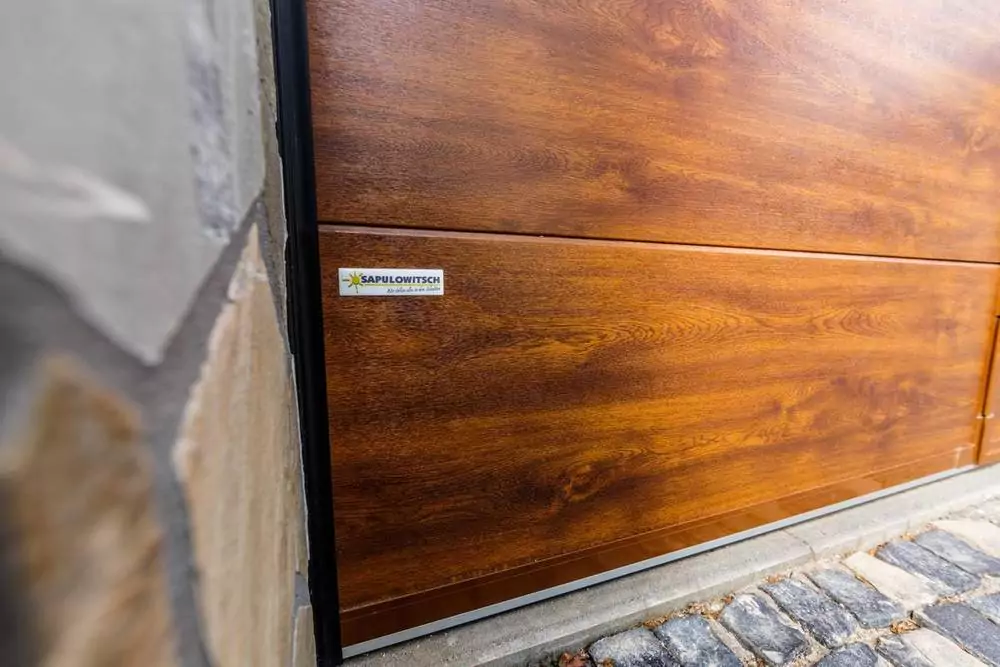 Abendliche Terrasse mit beleuchtetem rotem Sonnenschirm Braunes Garagentor in Holzoptik