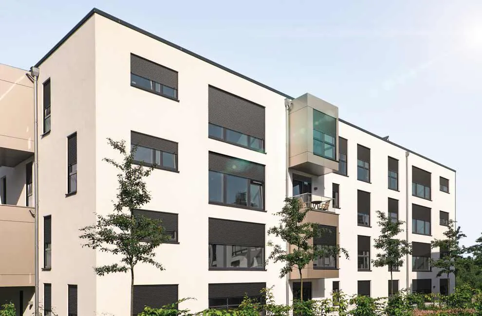 Weißes Mehrfamilienhaus mir dunklen Rollläden